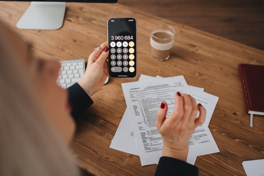 Hands working a calculator over a monthly budget sheet